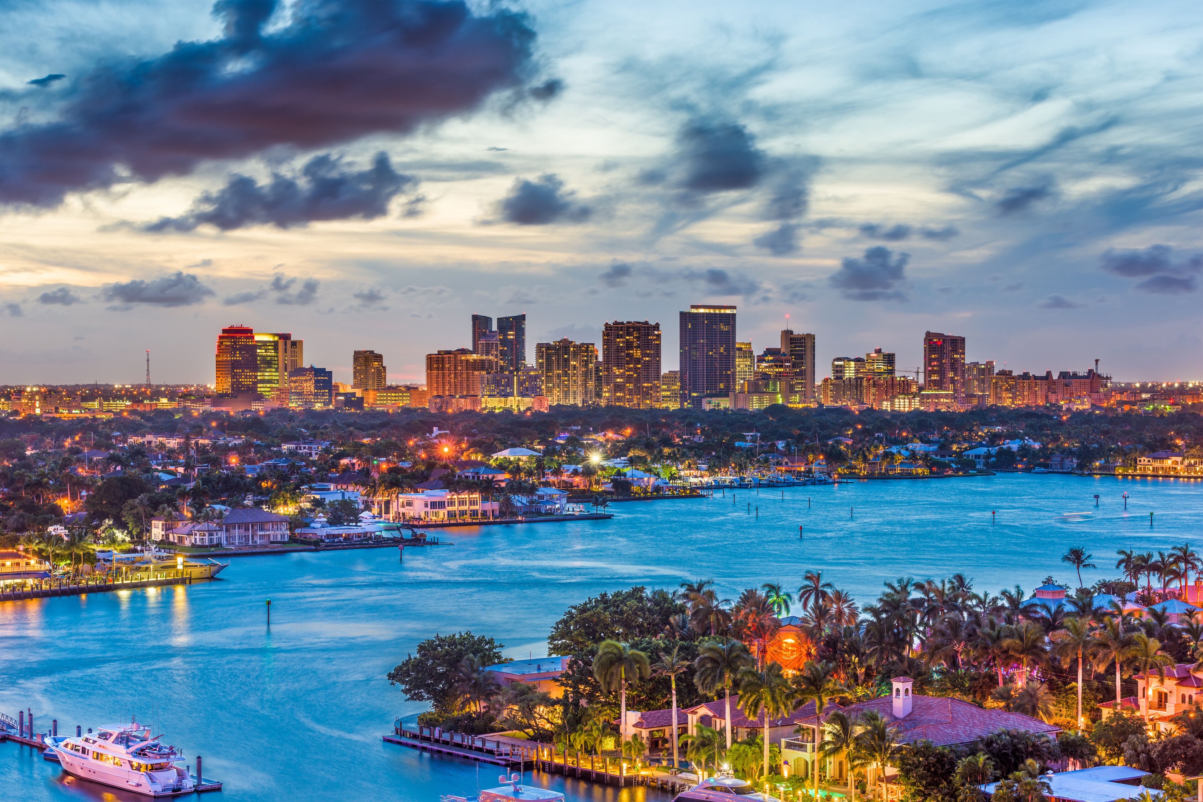 A city skyline at dusk with a harbor and boats.