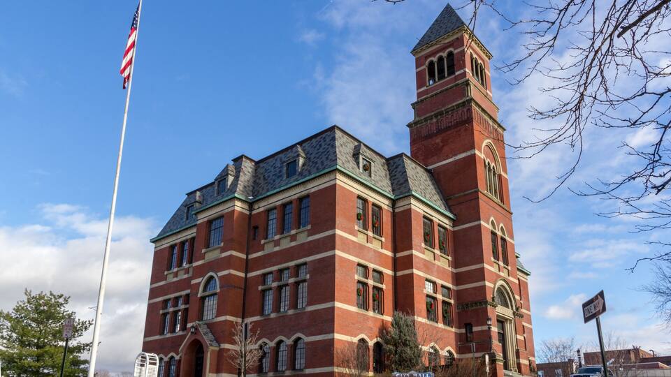 A large brick building with a tower and a flagpole.