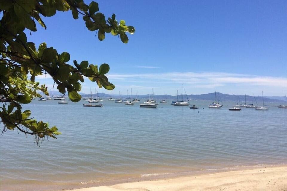 Une plage où des bateaux sont amarrés dans des eaux calmes, le tout étant entouré de montagnes.