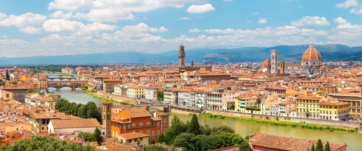A panoramic view of a historic city with a river, prominent domed buildings, and a bridge.