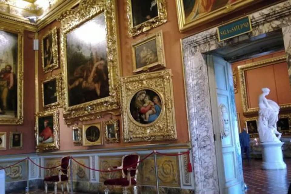 Una habitación ornamentada con cuadros dorados, una columna de mármol y una estatua.
