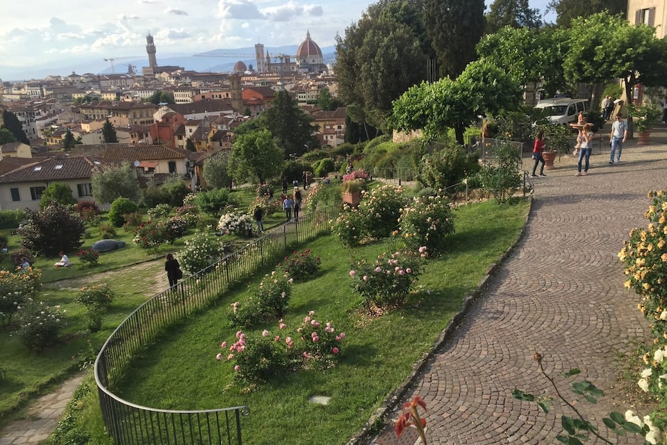 A park with a curved pathway, lush greenery, and a cityscape in the background.