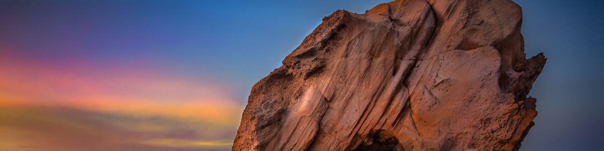 A large rock formation at sunset with a clear sky.