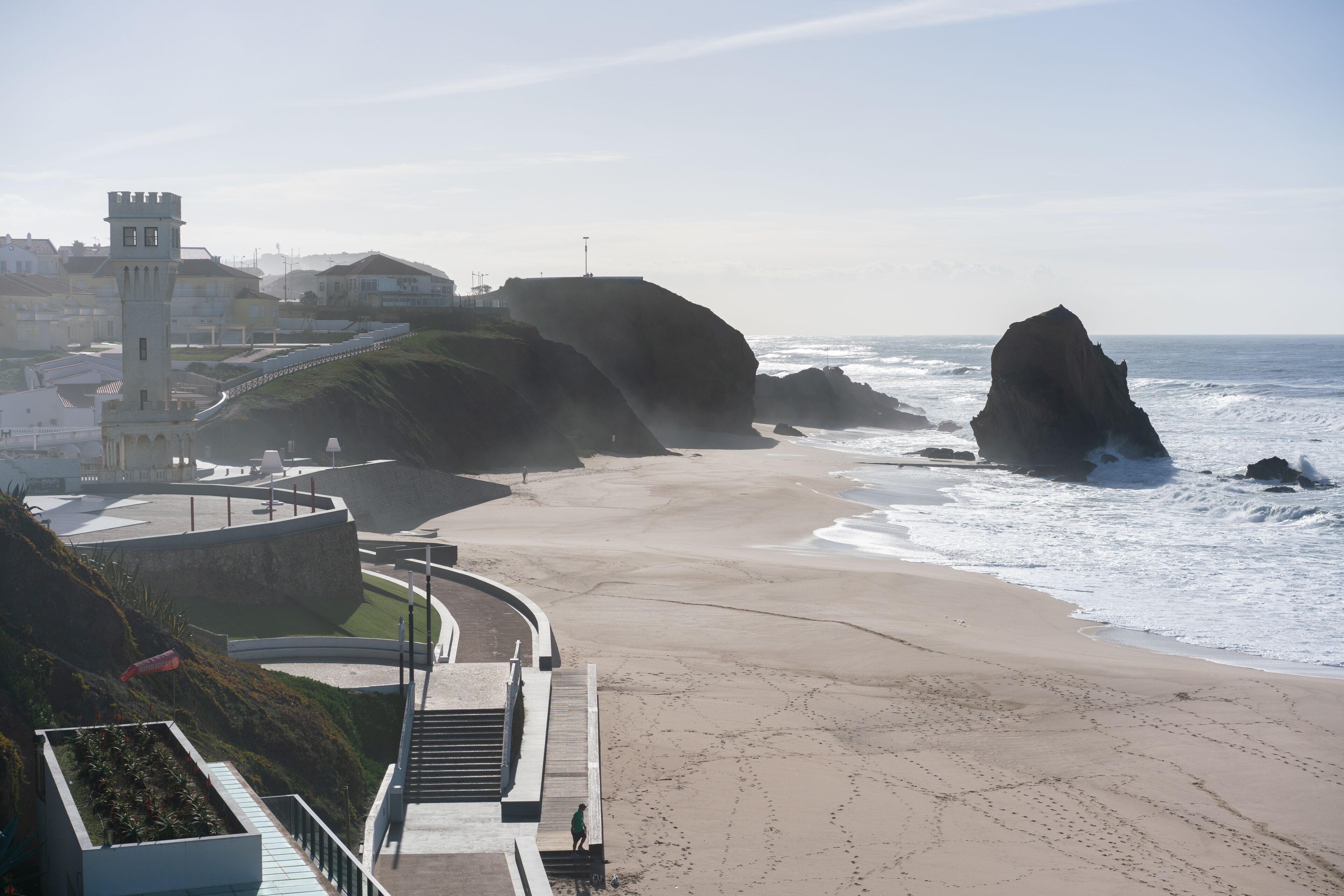 A coastal town with a lighthouse, a beach, and rocky outcrops.