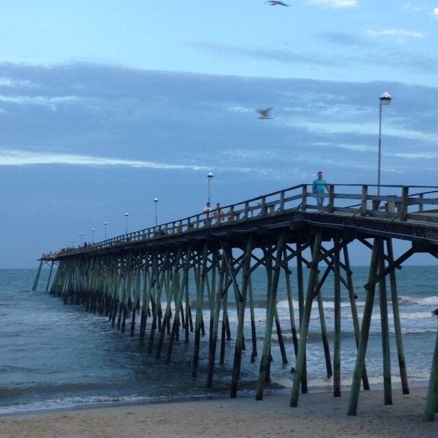 A pier extending into the ocean with people walking along it.
