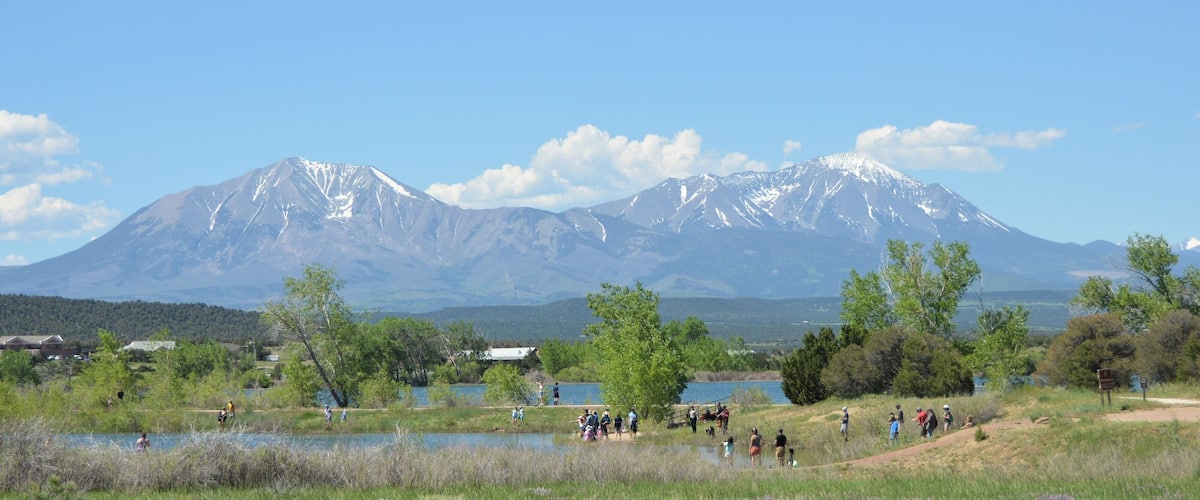A lake with people, a mountain range, and a small building.