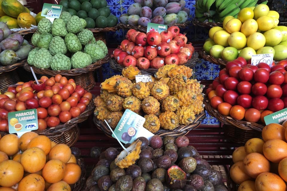 A fruit market with various fruits like mangoes, bananas, and oranges displayed in baskets.