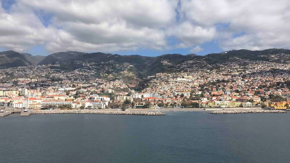 A coastal city with a harbor, surrounded by hills and mountains.