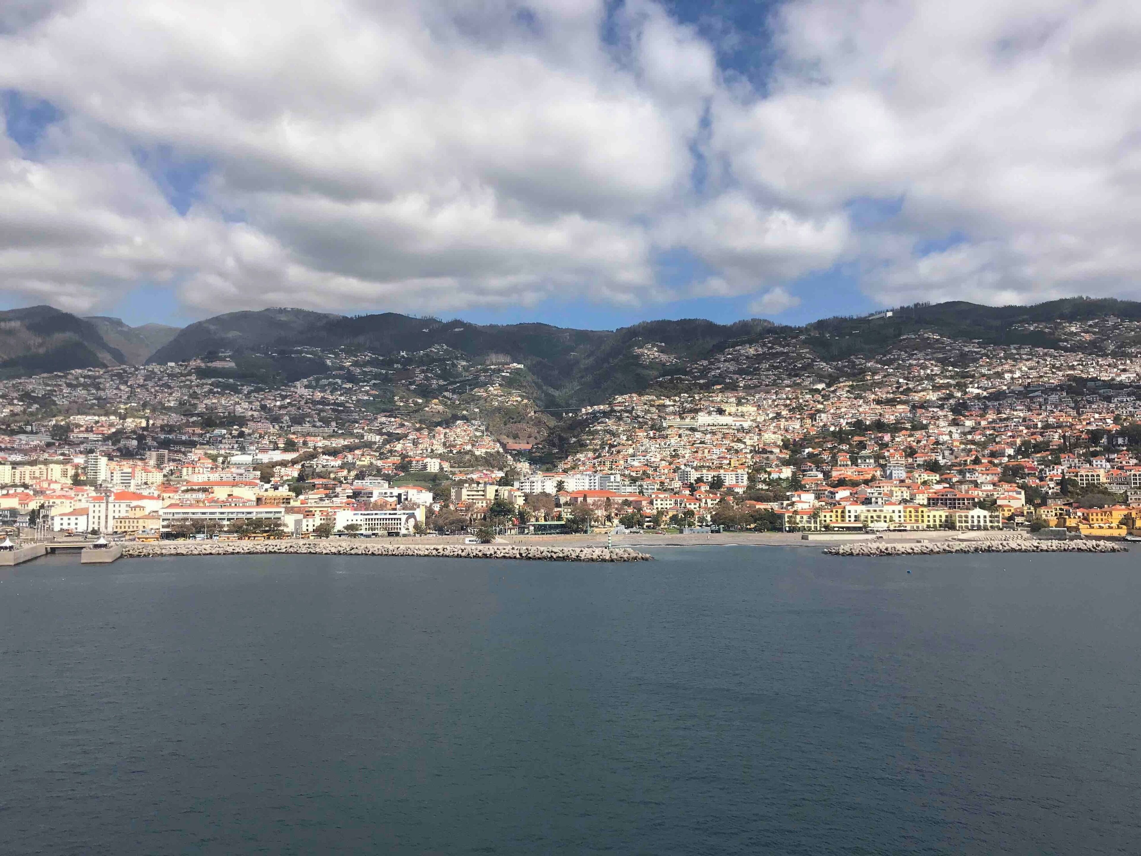 A coastal city with a harbor, surrounded by hills and mountains.