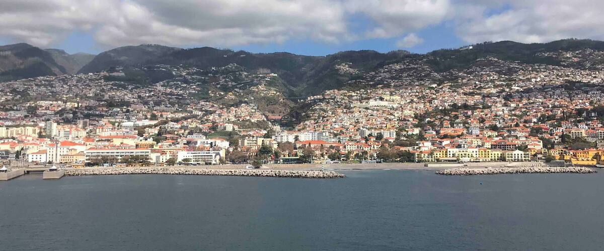 A coastal city with a harbor, surrounded by hills and mountains.
