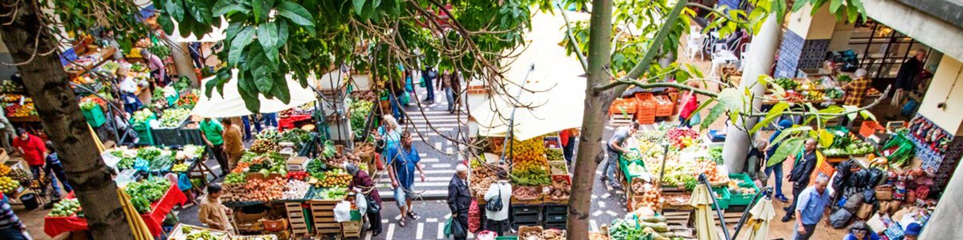 Un mercado al aire libre con varios puestos que venden frutas, verduras y otros productos frescos.