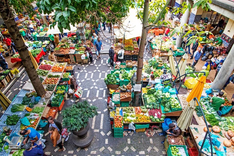 An outdoor market with various stalls selling fruits, vegetables, and other produce.