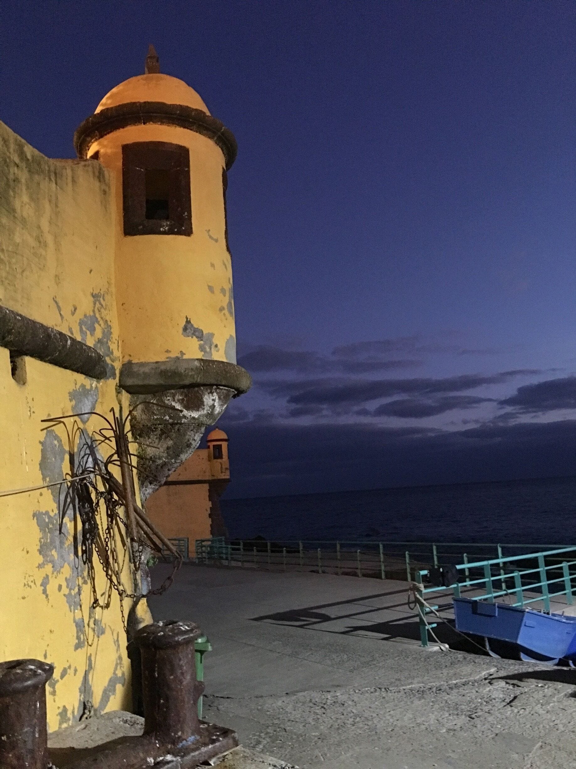 Un edificio costero con fachada amarilla y una pequeña torre, con vista al mar.