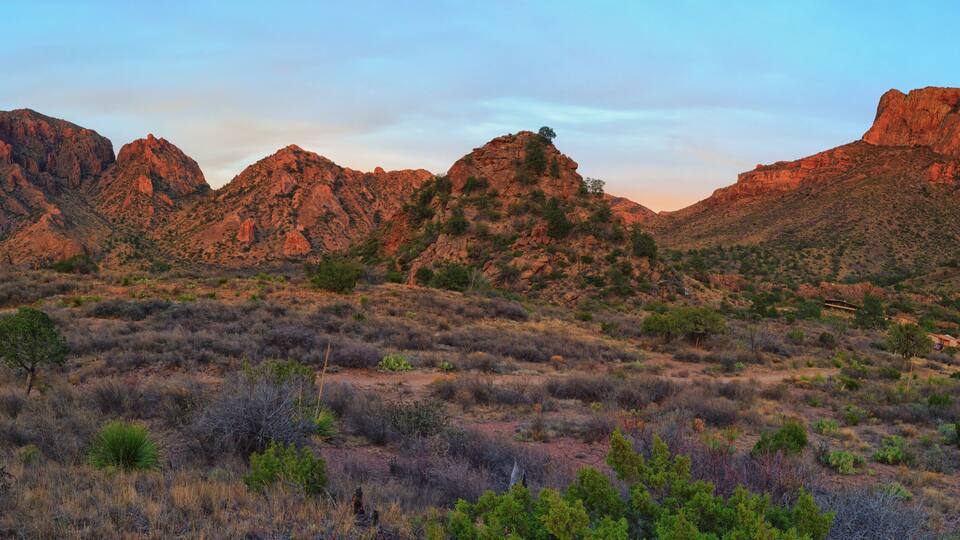 A rugged mountain range with sparse vegetation and a clear sky.