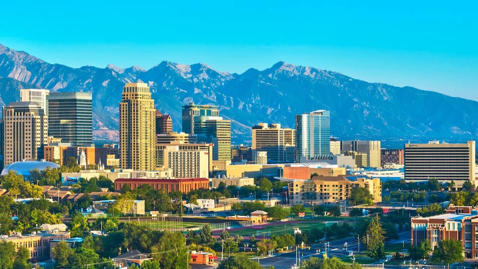 A cityscape with modern buildings and a mountain range in the background.