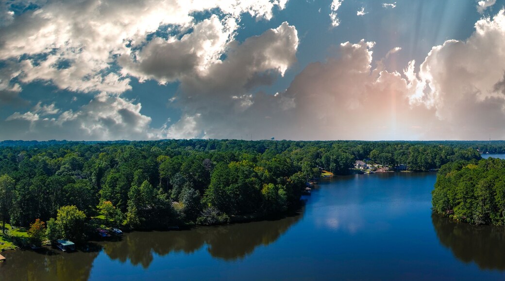 a stunning aerial panoramic shot of the blue waters of Lake Peachtree with vast miles of lush green trees and boats docked along the lake with powerful clouds in Peachtree City Georgia