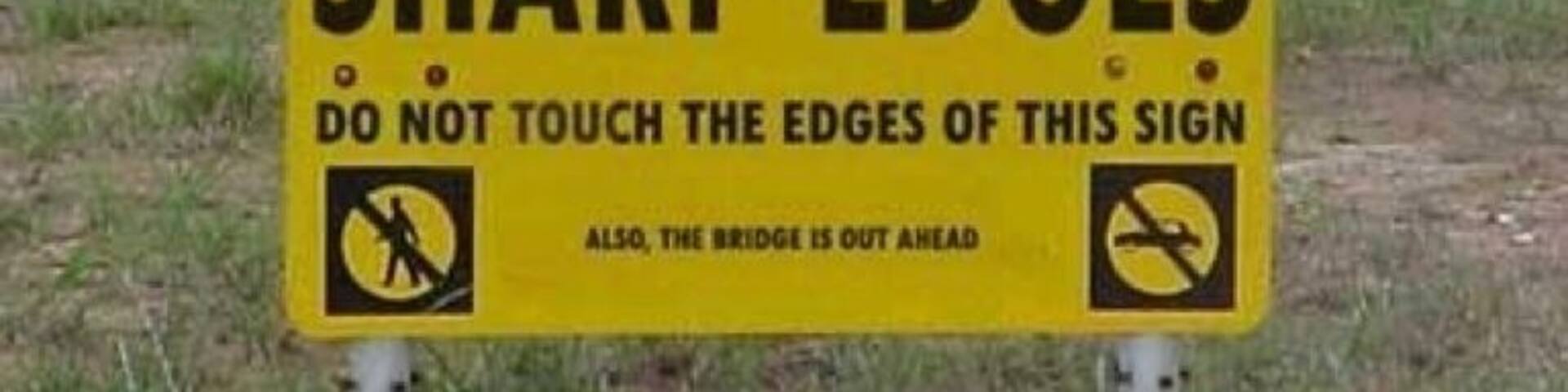A caution sign warning of sharp edges and a bridge out ahead.