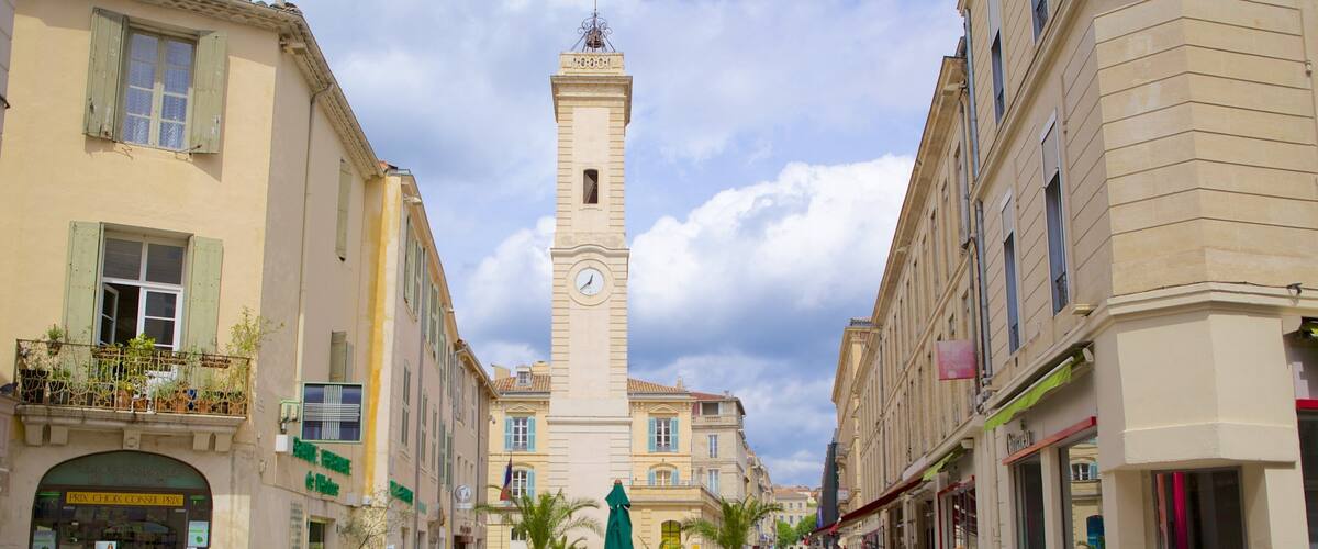 A bustling square with a prominent tower clock, cafes, and historic buildings.