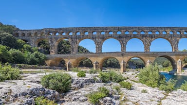 A stone aqueduct over a river with a boat on the water.