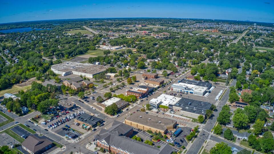 An aerial view of a town with a mix of commercial buildings, residential areas, and green spaces.