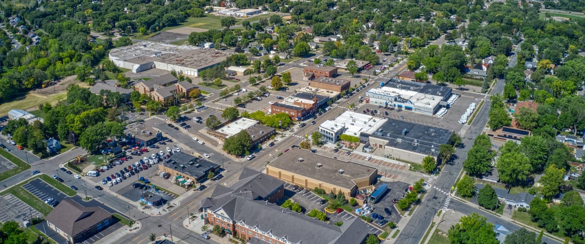 An aerial view of a town with a mix of commercial buildings, residential areas, and green spaces.
