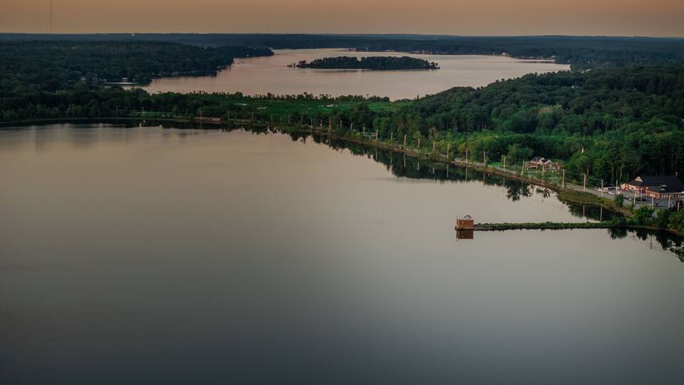 A calm lake surrounded by dense forests and a small island.