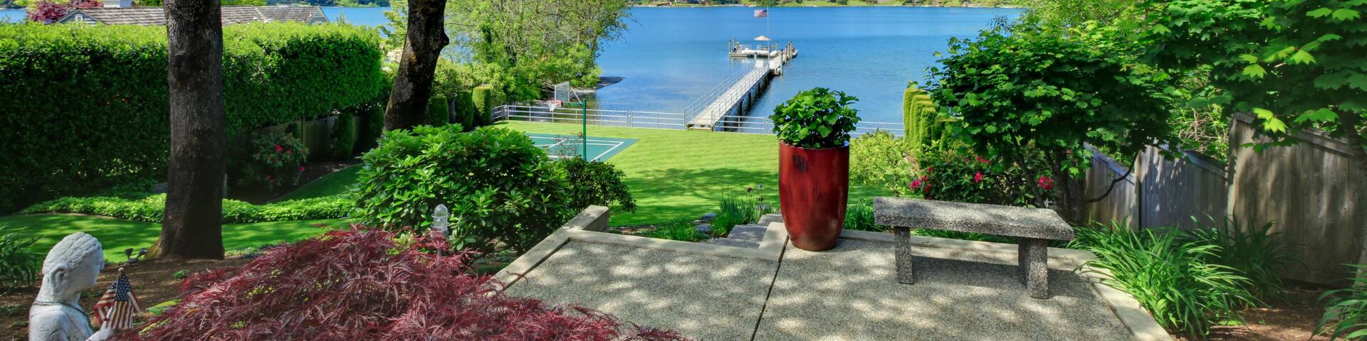 Tennis court with lake and bright green grass.