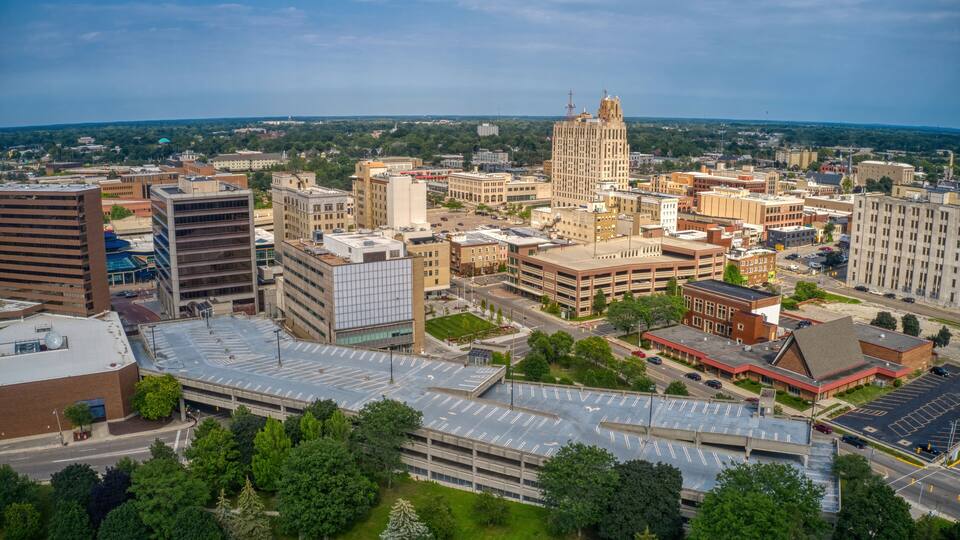 A cityscape with a prominent historic building, a large parking structure, and surrounding greenery.