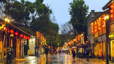 Calle mojada bordeada por edificios tradicionales y faroles rojos.