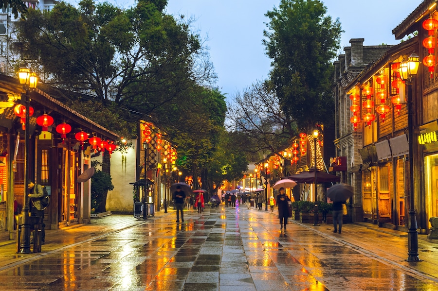 A wet street lined with traditional buildings and red lanterns.