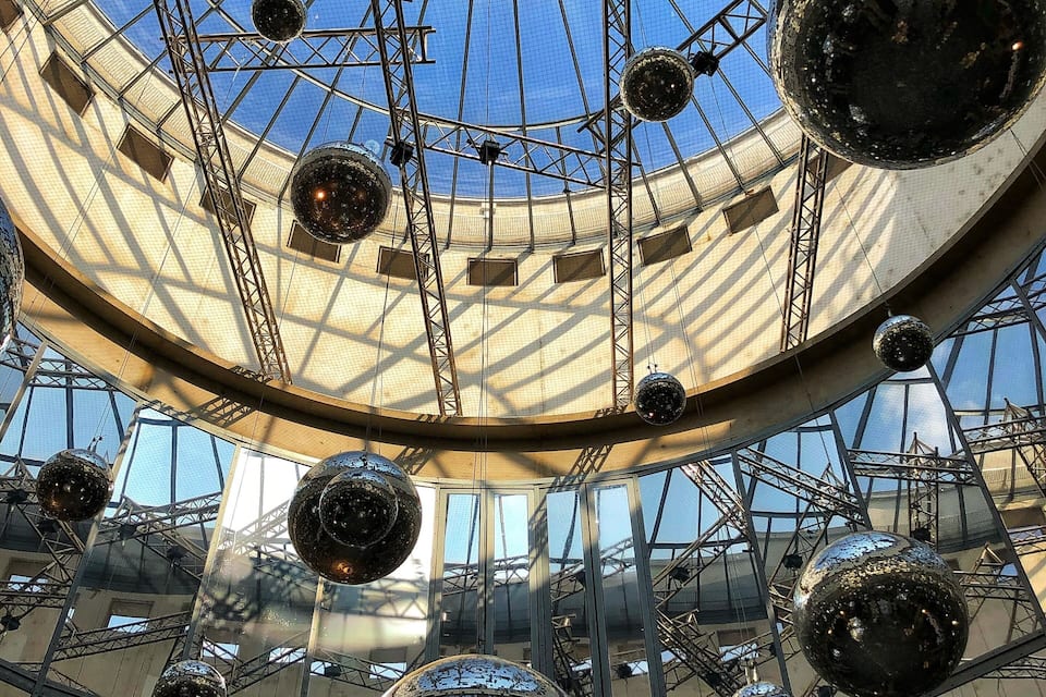 Una gran estructura interior amb sostre de vidre i múltiples miralls esfèrics.