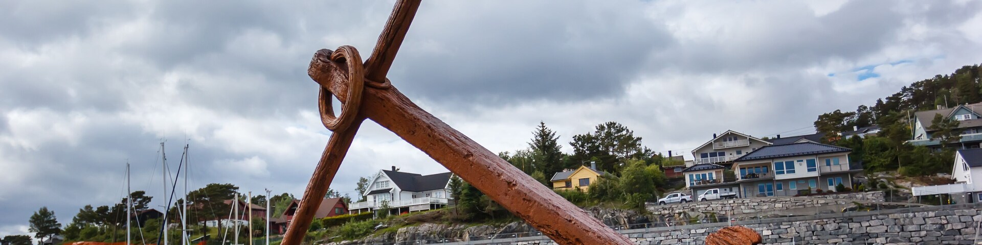 Huge rusty anchor on a pedestal on the banks of a fjord in Norway
