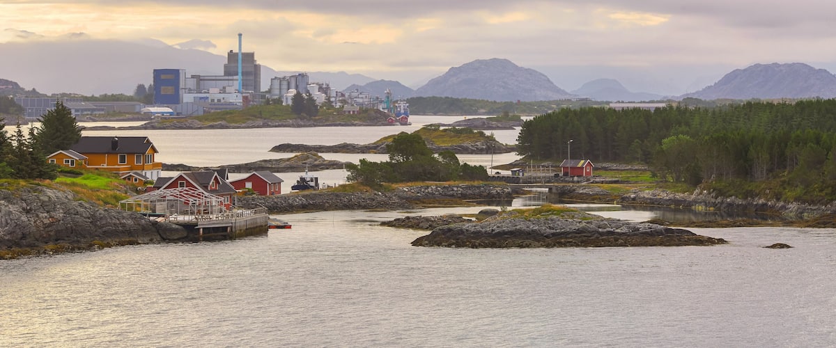 A coastal town with houses, a lighthouse, and industrial buildings.