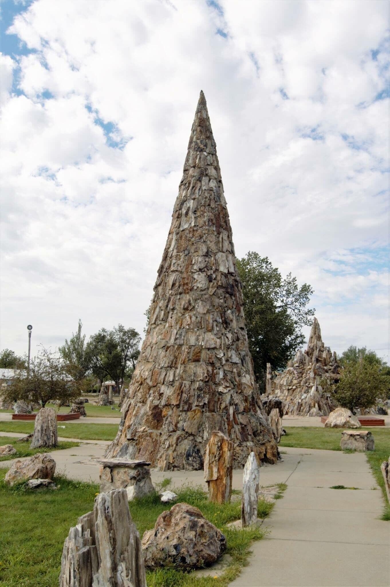 A large stone obelisk in a park with a pathway leading to it.
