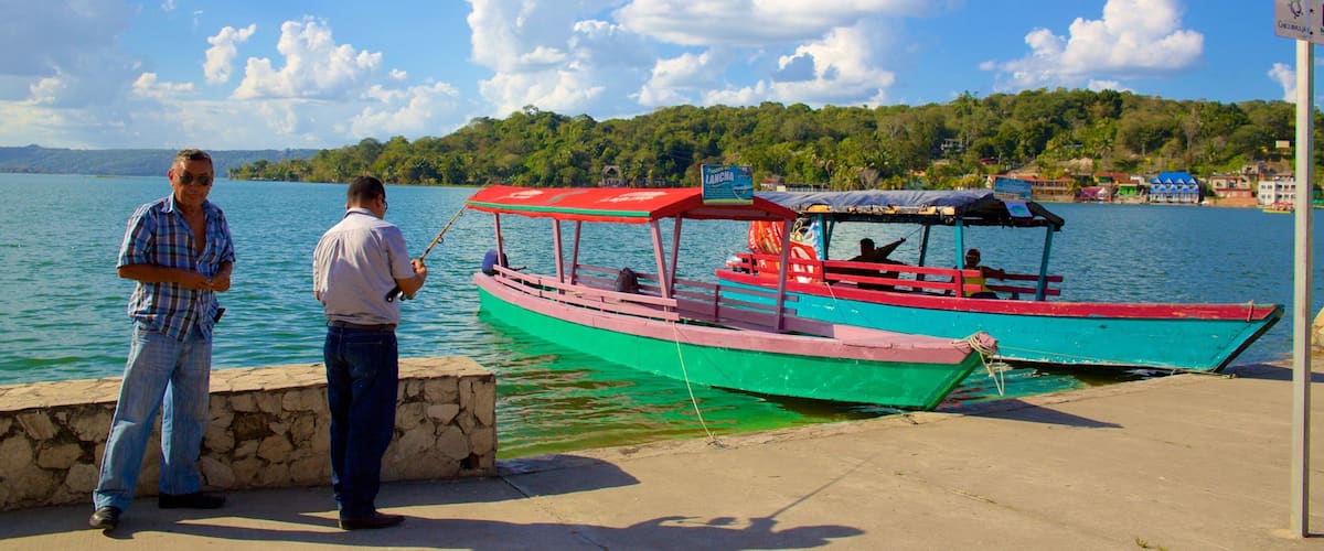 A man fishing by a dock with colorful boats in the background.