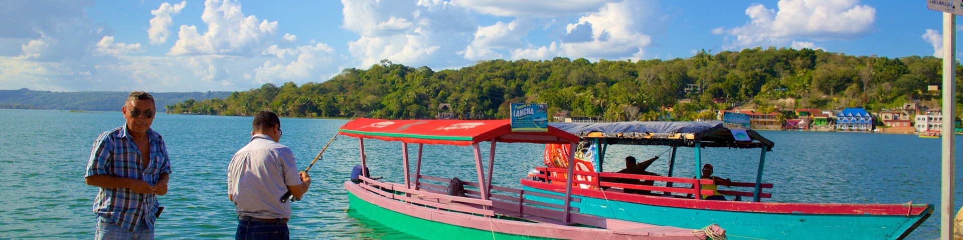 A man fishing by a dock with colorful boats in the background.