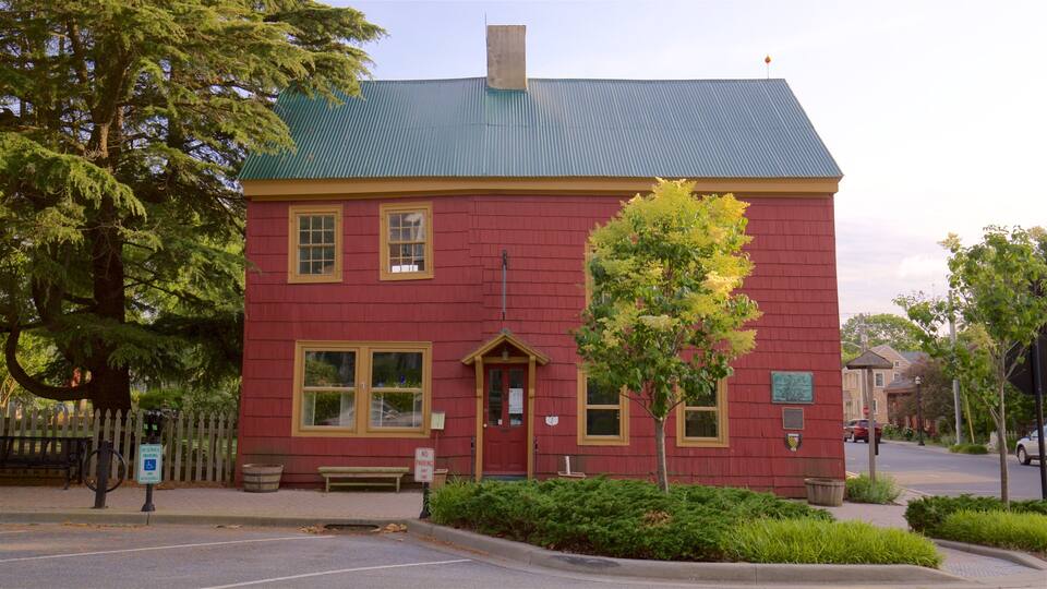 A red building with a green roof, a bench, and a tree in front.
