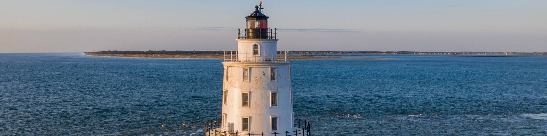 A lighthouse on a rocky outcrop surrounded by calm sea.