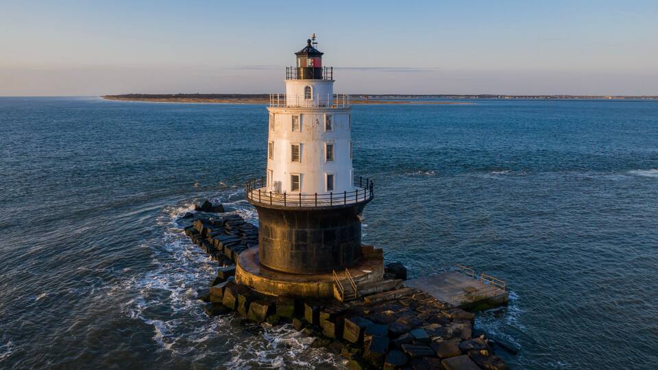 A lighthouse on a rocky outcrop surrounded by calm sea.