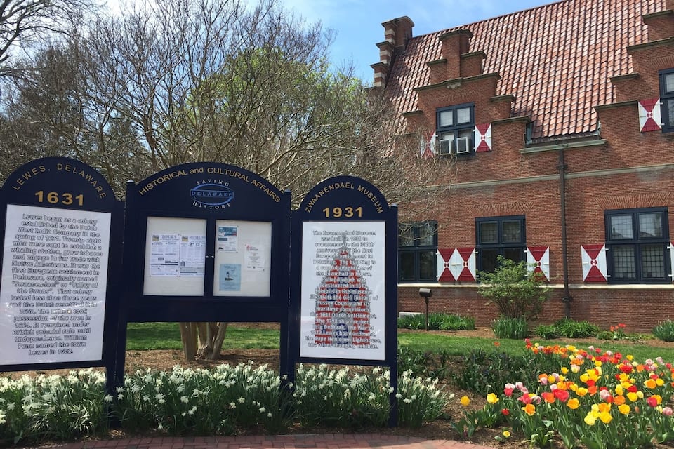 Historische markeringen uit 1631 en 1931, een bakstenen gebouw en een tuin met tulpen.