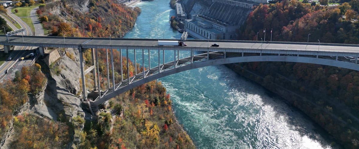 A bridge over a river with a dam and autumn foliage.