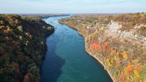 Aerial over the Niagara River and gorge between Lewiston, New York, United States and Ontario, Canada towards Lake Ontario. Shot during an autumn afternoon with colorful fall foliage trees in October.