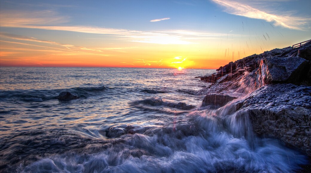 Beautiful Sunrise Beach Background. Waves crash onto the rocks of a Lake Huron beach with a sunrise horizon in the background. Lexington, Michigan.