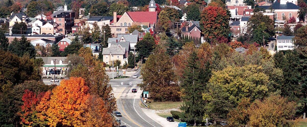 A town with autumn foliage, a church steeple, and a cemetery.