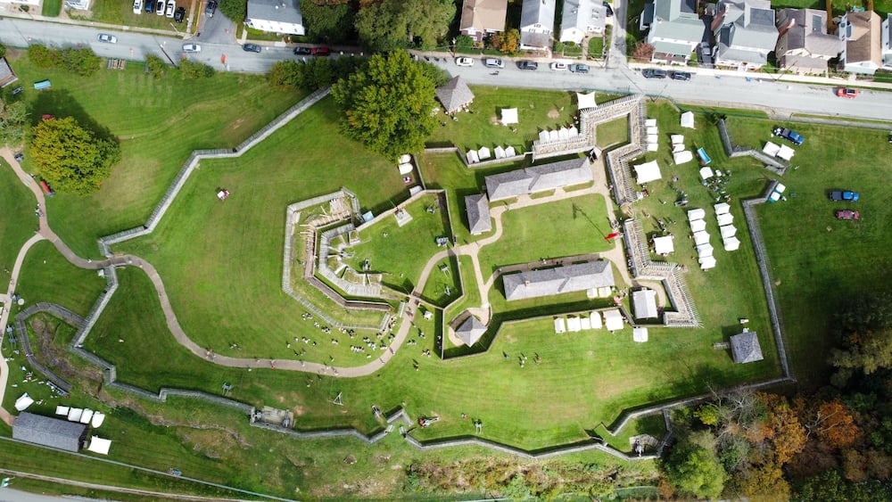 A large, enclosed park with a central fort-like structure, surrounded by a well-maintained lawn and a road running alongside.