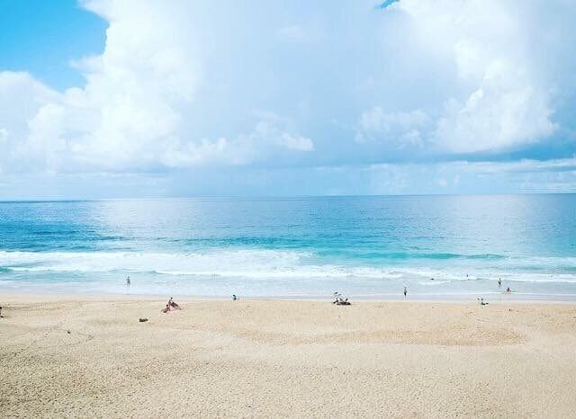 Una playa con cielo despejado y mar tranquilo.