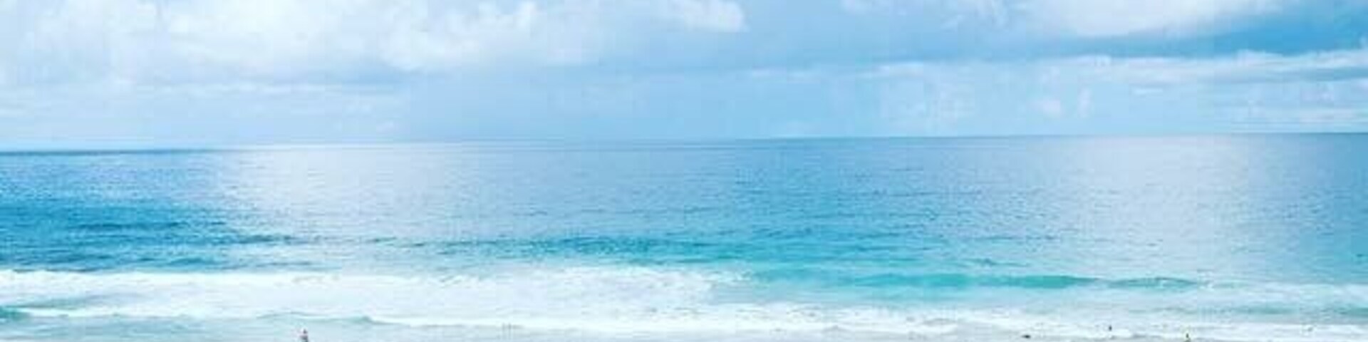 Una playa con cielo despejado y mar tranquilo.