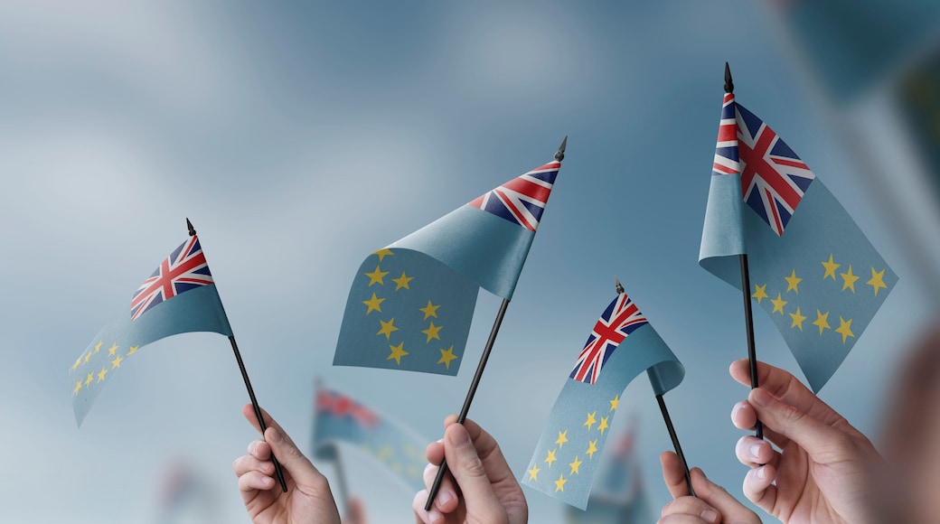 A group of people holding small flags of the Tuvalu in their hands