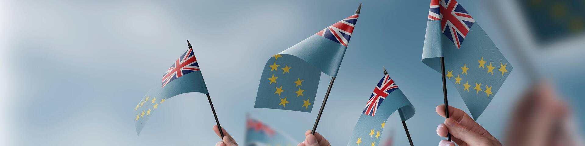 A group of people holding small flags of the Tuvalu in their hands