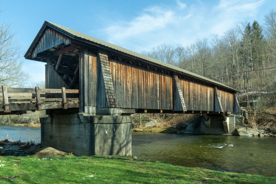 Un puente cubierto de madera sobre un río, con base de hormigón.